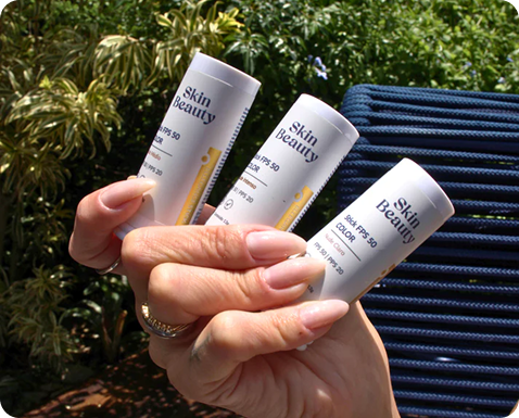 Mão segurando três produtos Skin Beauty em frente a plantas